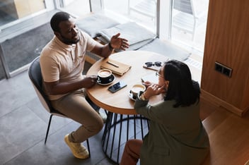 2 people talk and share what’s going on in a coffee shop