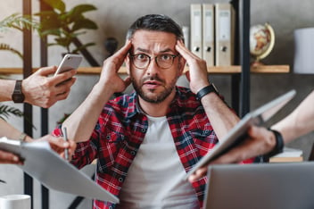 Man looking overwhelmed by connectivity and stress at work